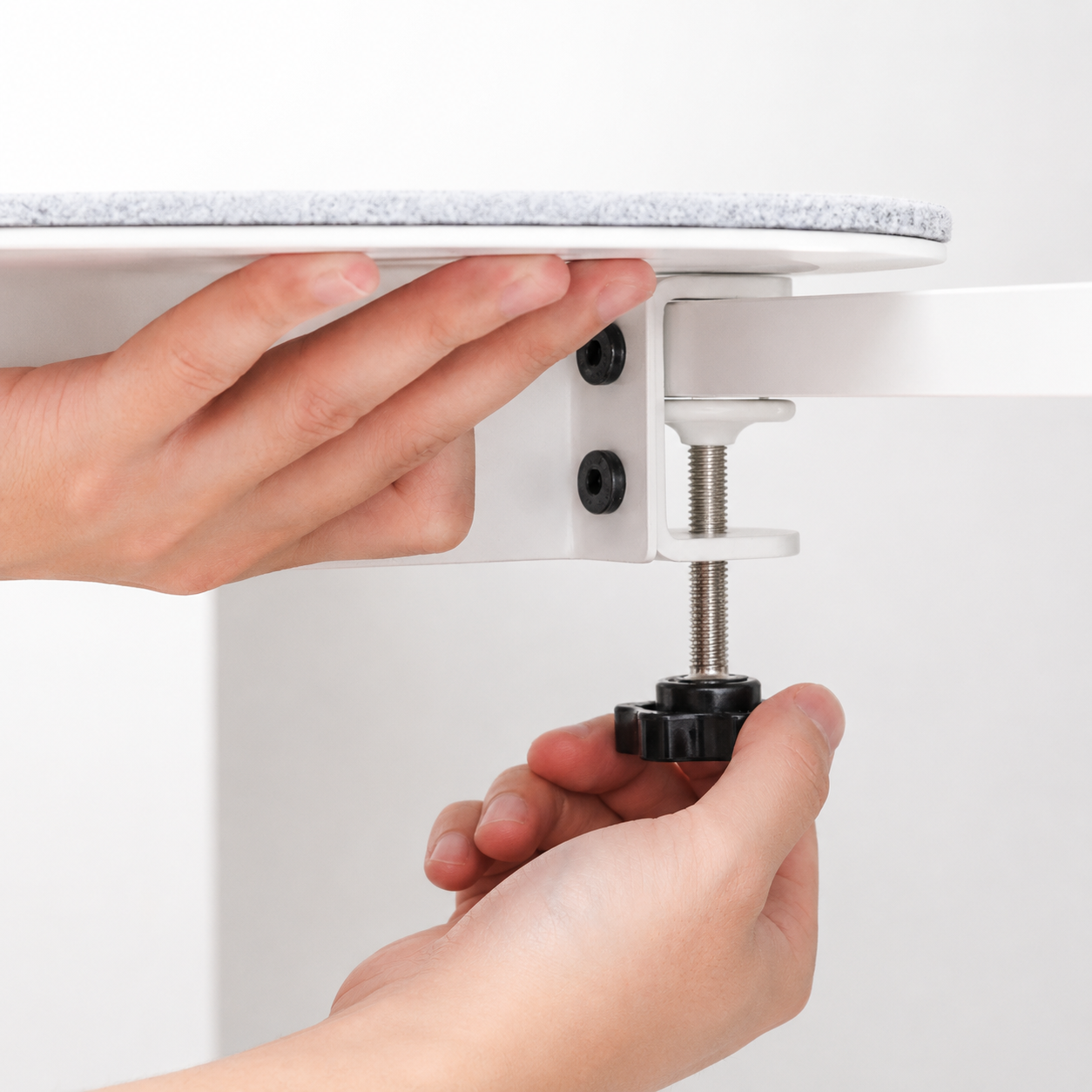 Hands tightening the white cat shelf clamp under a furniture edge
